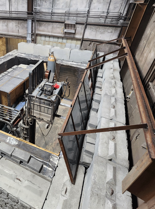 Enclosed industrial bay with concrete block walls and rusted steel framing for shielding and support.