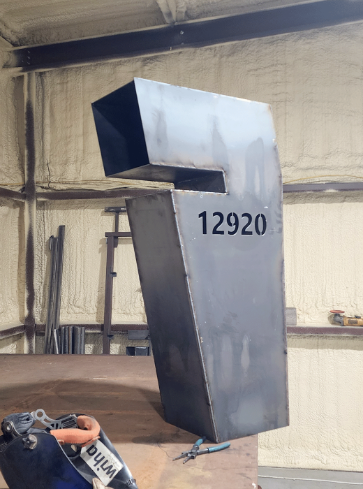 Custom fabricated steel address monument with cutout top, labeled 12920 in a metal shop.